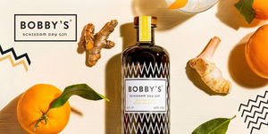 BOBBY'S schiedam dry gin bottle lied down with decorative oranges and ginger roots
