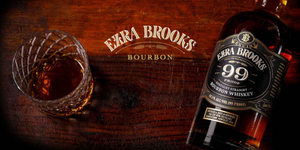 Ezra Brooks 99 proof whiskey bottle and glass on a wooden table