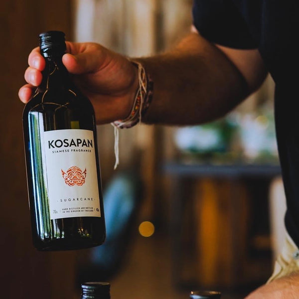 a hand holding a bottle of Kosapan Sugarcane Rum