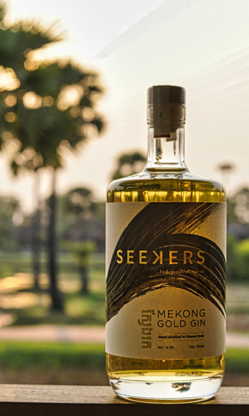 Seekers Mekong Gold Gin golden bottle shining with palm trees and vegetation in background